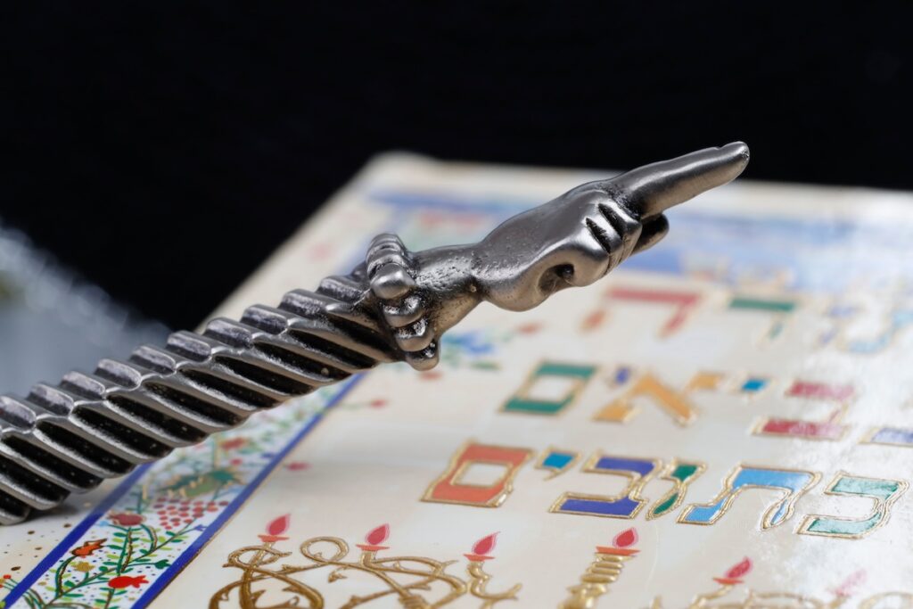 A silver Yad Jewish ritual pointer on a Torah