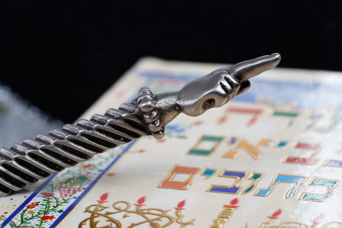 A silver Yad Jewish ritual pointer on a Torah