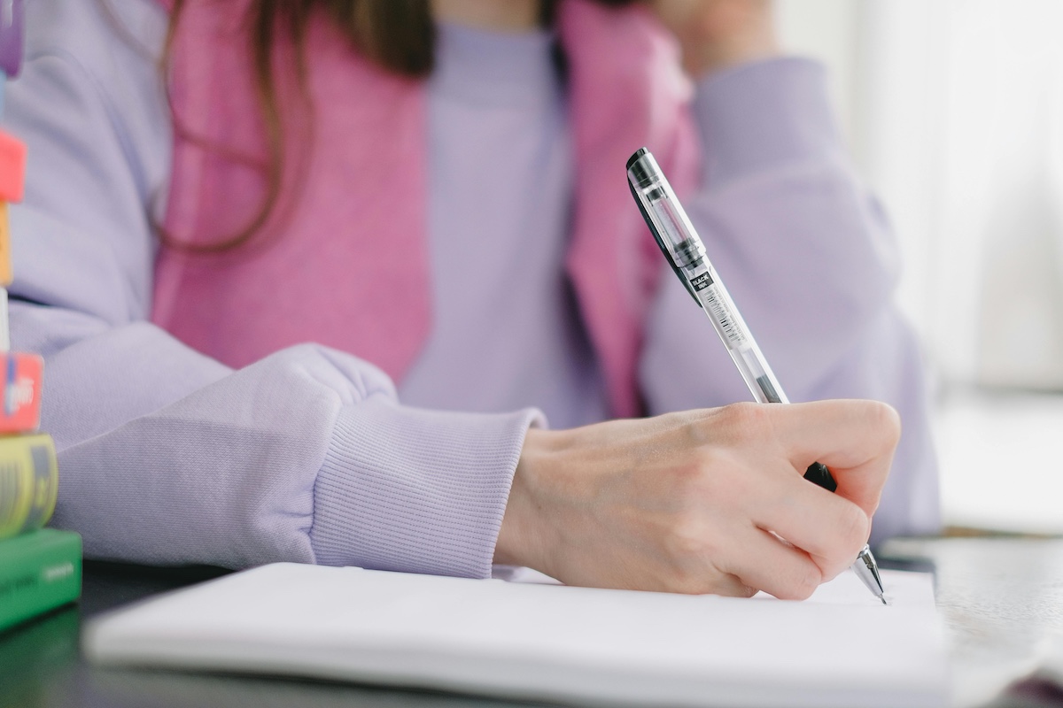 Woman Wearing Light Purple Sweater, Writing in a Notebook